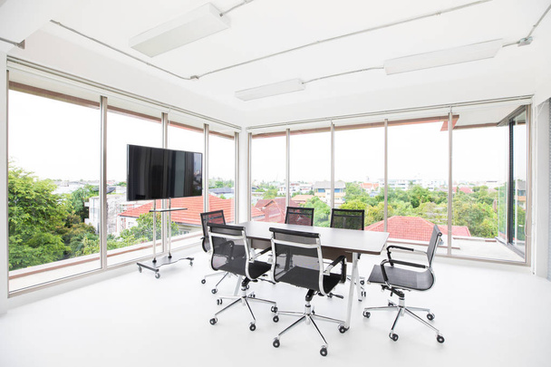 Groep conferentietafel en stoelen in wit en brede kantoor met TV-scherm zonder dat iemand op kamer - Foto, afbeelding