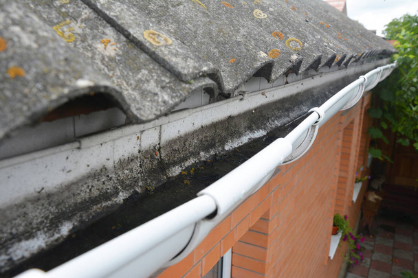 Çatı Oluk çamura. Asbest çatı yağmur oluk ile. Temizlik cilt payı. - Fotoğraf, Görsel