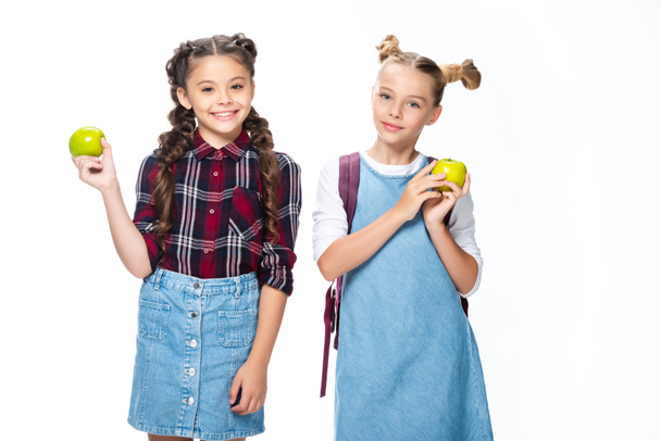 crianças em idade escolar sorrindo segurando maçãs e olhando para a câmera isolada no branco
 - Foto, Imagem