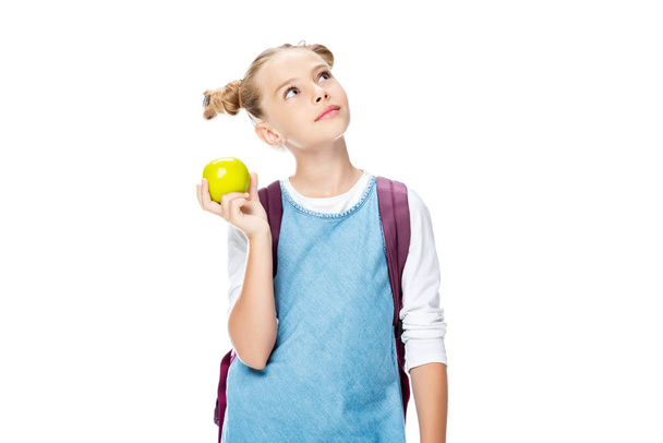 niño de la escuela sosteniendo manzana y mirando hacia arriba aislado en blanco
 - Foto, Imagen