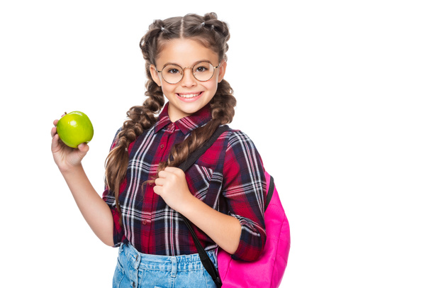 Lächelndes Schulkind mit Rucksack, der Apfel isoliert auf weißem Grund hält - Foto, Bild