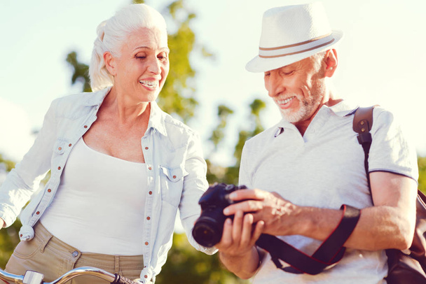 Radiant senior couple smiling while looking though photos - Foto, imagen
