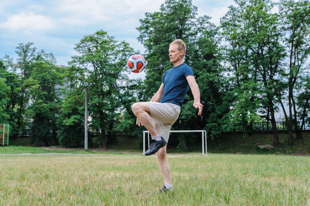Football game. The man is kicking a soccer ball by a knee. - Fotoğraf, Görsel