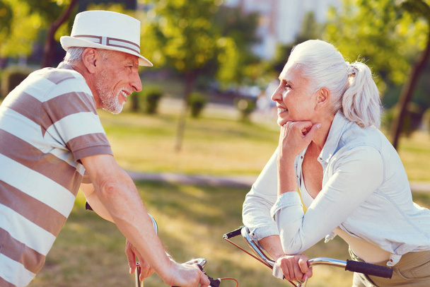 Loving senior couple chatting after bicycling in park - Foto, Imagem