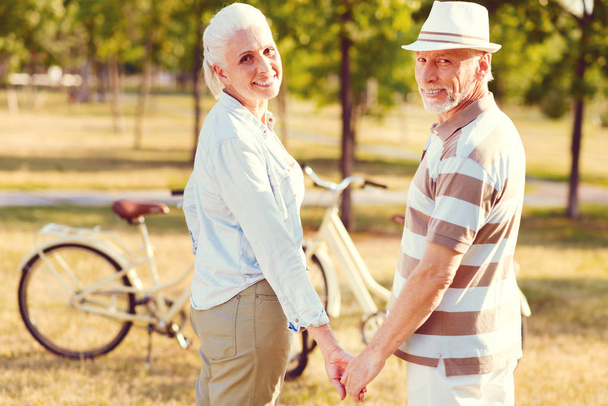 Vrolijke senior paar glimlachen terwijl de handen bij elkaar te houden - Foto, afbeelding