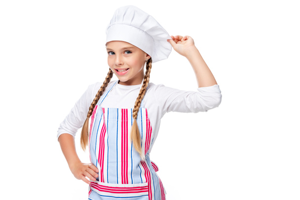 scholier poseren in schort en chef-kok hoed geïsoleerd op wit - Foto, afbeelding