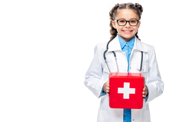 escolar en traje de médico sosteniendo botiquín de primeros auxilios aislado en blanco
 - Foto, imagen