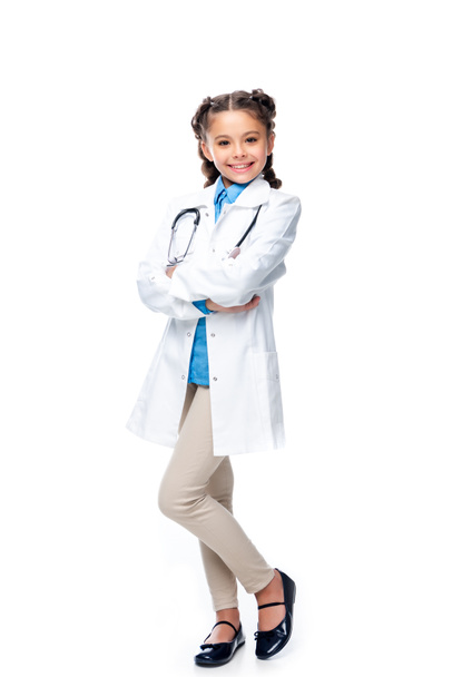 smiling schoolchild in costume of doctor standing with crossed arms isolated on white - Foto, Imagen