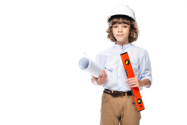 schoolboy in costume of architect and helmet holding blueprints and spirit level isolated on white - Fotografie, Obrázek