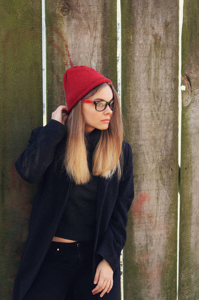 Stylish blond woman in glasses and red warm hat posing outdoors - Photo, Image