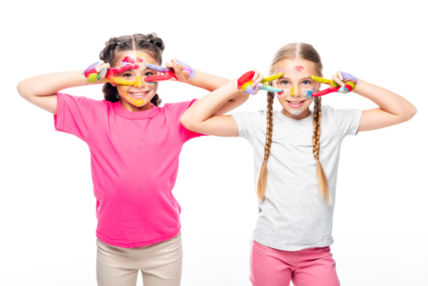 lachende schoolkinderen kijken door geschilderde vingers geïsoleerd op wit - Foto, afbeelding