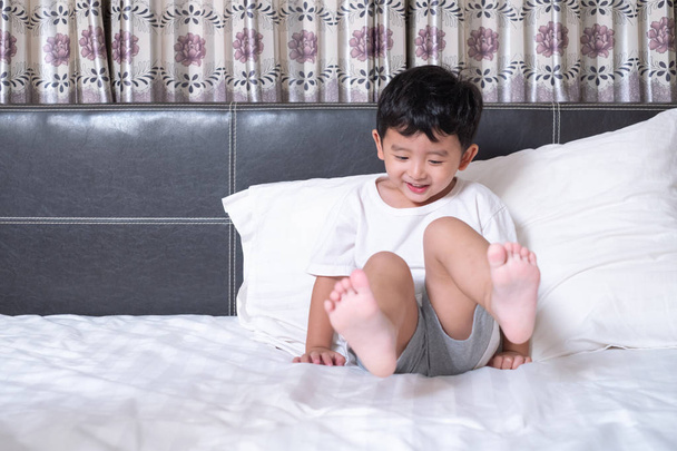 3 years old little cute Asian boy at home on the bed, kid lying playing and smiling on white bed with pillow and blanket, with copy space for add text. - Photo, Image