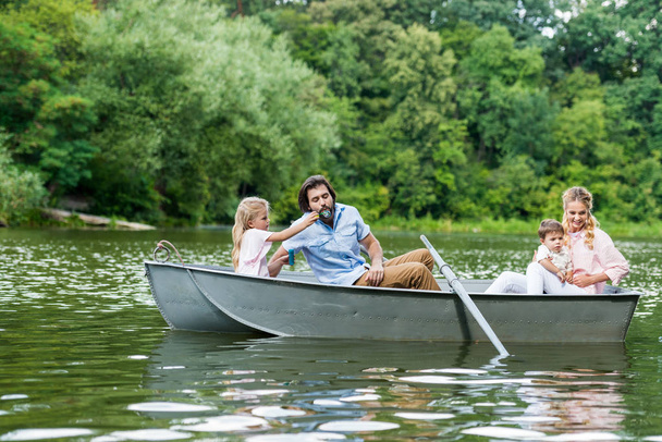 beautiful young family spending time together in boat on lake at park - Foto, Imagem