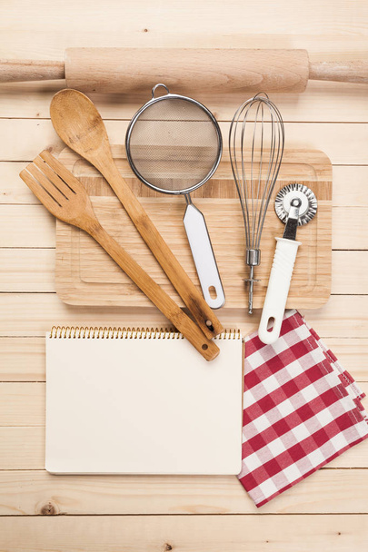 Wooden spoons and other cooking tools with red napkins on the kitchen table. - Foto, Bild