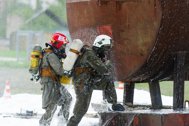  Двоє рятувальників усувають наслідки хімічної аварії. Вправи рятувальників на хімічному заводі для збереження промислового об'єкта
. - Фото, зображення