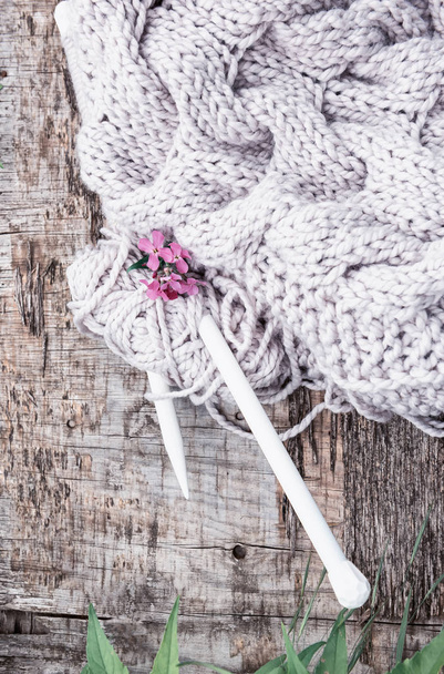 Gray knitted rough knitting threads and knitting needles on a rough wooden background. - 写真・画像