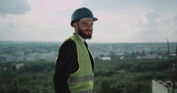 happy and confident architect with safety helmet in construction site, smiling at camera. 4k. slow motion - Filmati, video