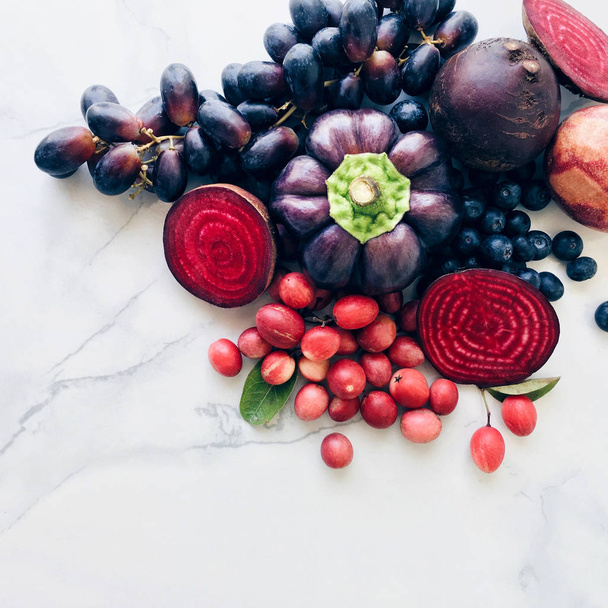 Purple mixed fruit and veggie on a marble background, top view copy space - Foto, afbeelding