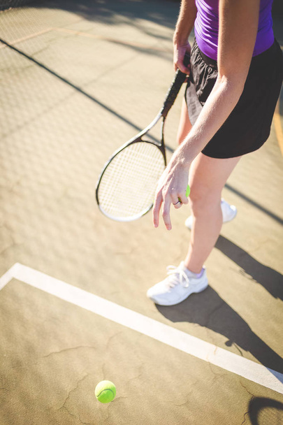 Close up image of a female tennis player playing tennis on a court in bright sunlight - Фото, изображение