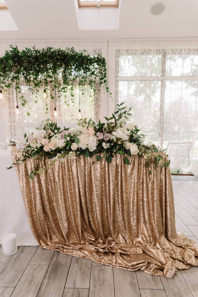 The golden cloth on a wedding table and a lot of beautiful wedding floristics - Photo, Image
