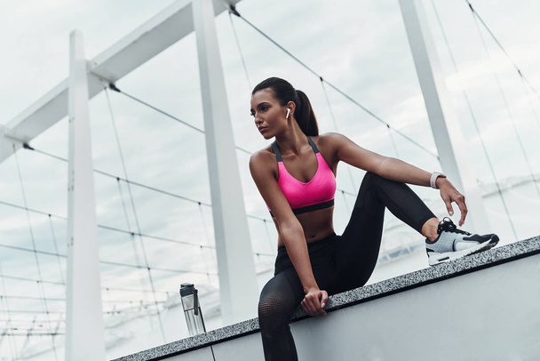 woman in sports clothing resting on roof of building - Foto, Imagen