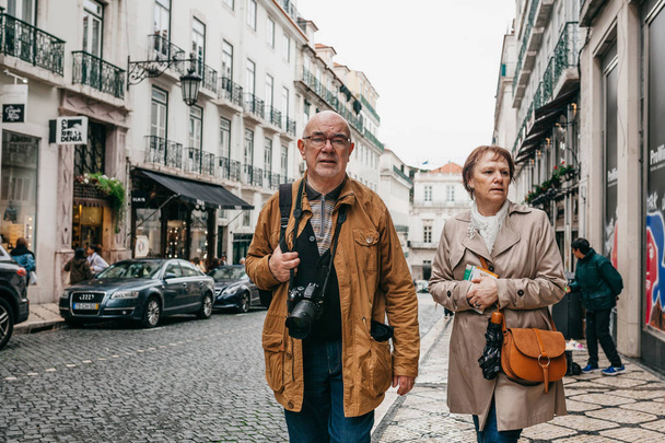An elderly couple of European tourists are walking around Lisbon in Portugal. - Фото, зображення