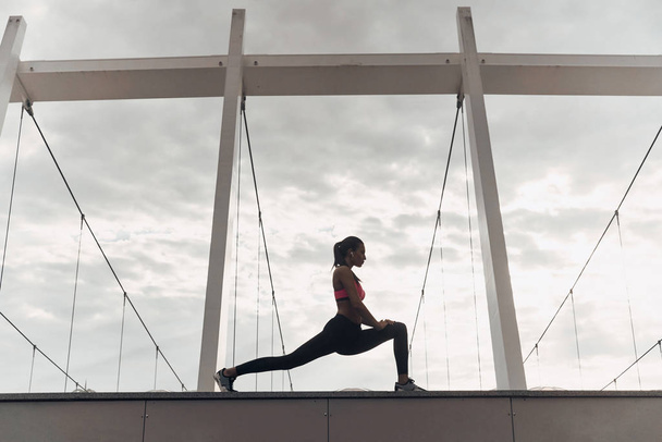 sportive woman stretching outdoors on roof of modern building - Photo, image