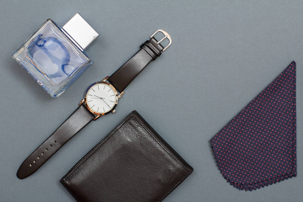 Leather purse, watch with a black leather strap, cologne for men and handkerchief on grey background. Accessories for men. Top view - Photo, Image
