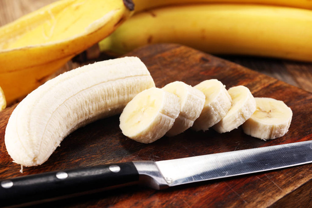 Egy banánt és egy szeletelt banánt egy táblázatra termékeinek - Fotó, kép