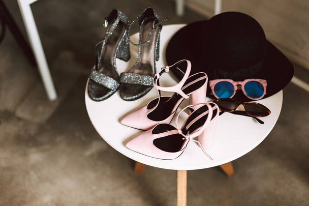 Close up sapatos modernos no calcanhar, óculos de sol e chapéu preto em stand no showroom isolado
 - Foto, Imagem