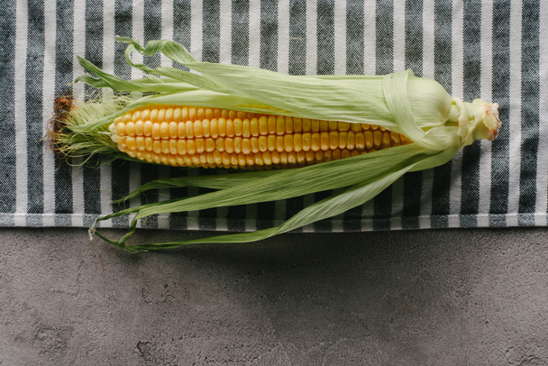 top view of fresh corn cob on linen on concrete tabletop - Фото, изображение