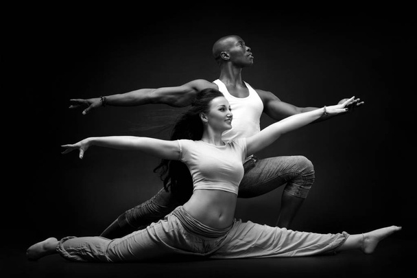 Black man and white woman in a beautiful dance position on a black background. - Fotoğraf, Görsel