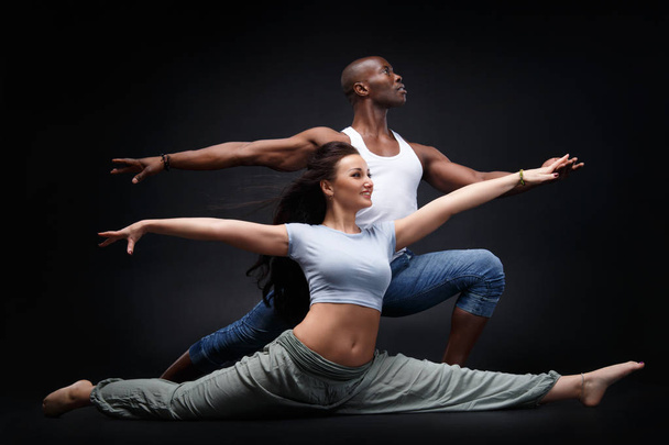 Uomo nero e donna bianca in una bella posizione di danza su uno sfondo nero
. - Foto, immagini