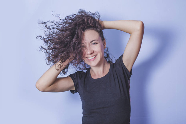 Young woman with curly hair on blue background - Valokuva, kuva