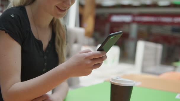 Γκρο πλαν του γυναικείου χεριού με smartphone στο χέρι στο φόντο του πίνακα καφέ - Πλάνα, βίντεο