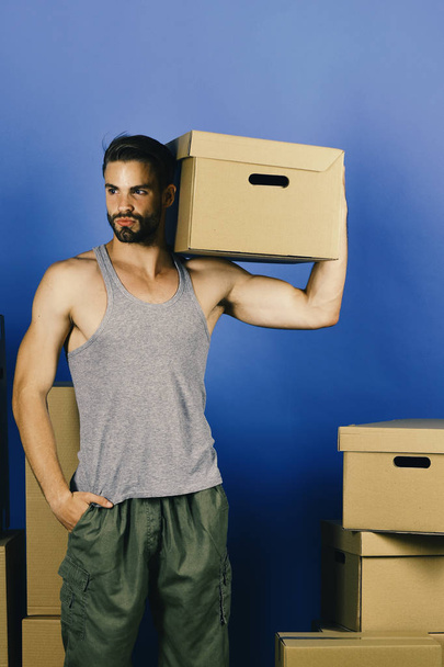 Levering en verplaatsen in concept: fit man met karton  - Foto, afbeelding