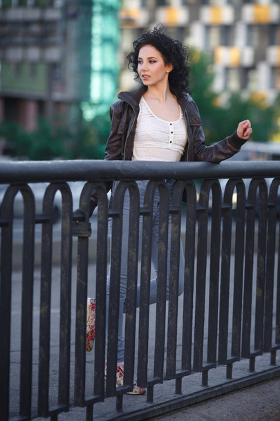 Beautiful young brunette girl on a city bridge. - Zdjęcie, obraz
