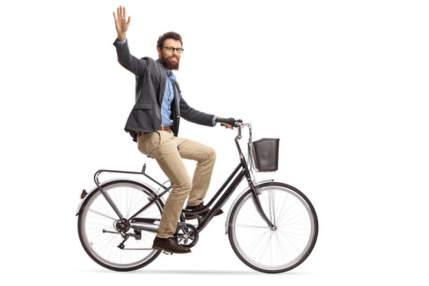 Bearded man riding a bicycle and waving at the camera isolated on white background - Фото, изображение