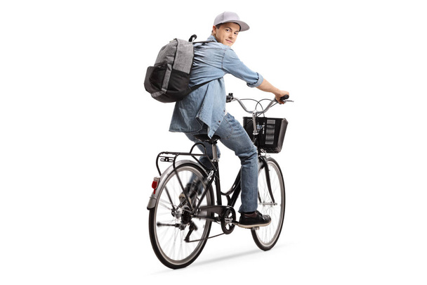 Teenager with a backpack riding a bicycle isolated on white background - 写真・画像