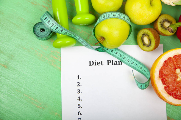 Food and sheet of paper with a diet plan on a green wooden background. Concept of diet and healthy lifestyle. - Фото, зображення