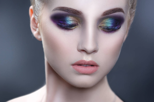 Beauty portrait of a beautiful girl with a bright make-up of peacock coloring isolated on a gray background. - 写真・画像