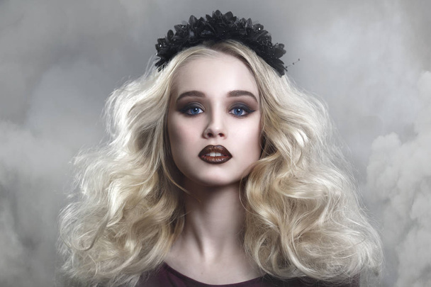 Beauty portrait of a beautiful young blonde woman with gothic make-up and decorative wreath in a puff of smoke. - Zdjęcie, obraz
