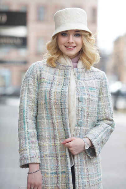 Beautiful stylish blond woman in coat and hat on city street. - Foto, imagen