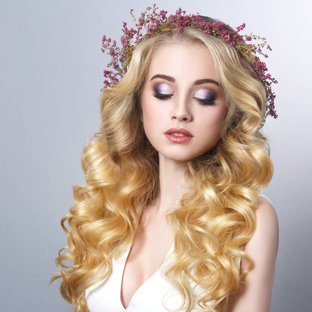 Beauty portrait of a blonde girl with chic curls in a wreath of heather isolated on a gray background. - Zdjęcie, obraz