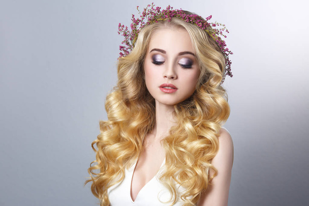 Beauty portrait of a beautiful blonde girl with chic curls and a wreath of heather isolated on a gray background. - Photo, Image