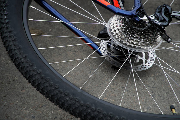 Stile di vita attivo: la ruota posteriore di una bicicletta si trova sull'asfalto. Ruota, pignone e catena per biciclette
 - Foto, immagini