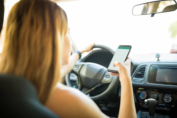 Vue arrière de la femme conduisant une voiture et utilisant la navigation sur son smartphone
 - Photo, image