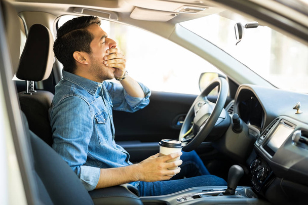 Молодий чоловік відчуває втому і позіхання під час водіння автомобіля
 - Фото, зображення