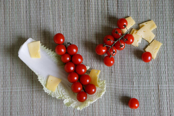 Une branche de tomates cerises, de fromage et de chou chinois repose sur une surface naturelle en bois
. - Photo, image