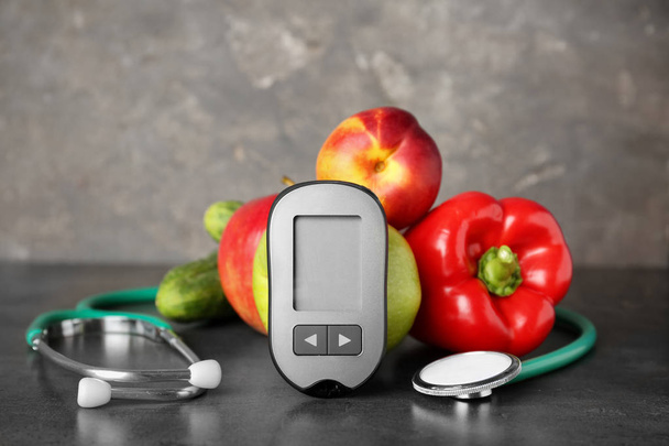 Digital glucometer, stethoscope, fruits and vegetables on table. Diabetes concept - Foto, Imagem